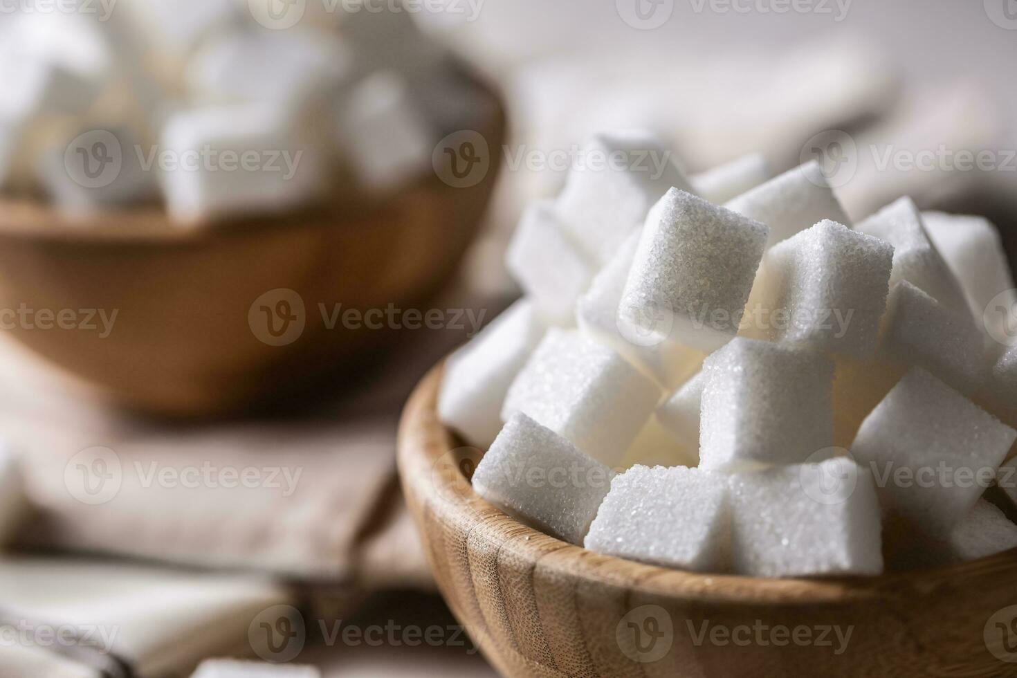 wit suiker kubussen in een houten kom Aan de tafel foto