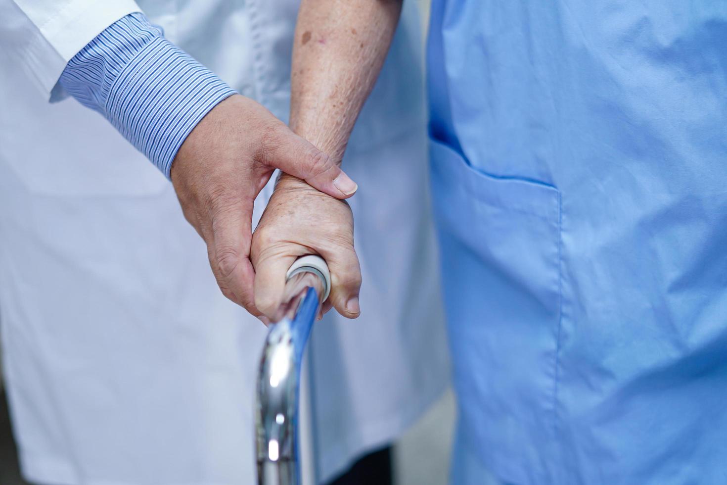 arts help aziatische senior of oudere oude dame vrouw patiënt lopen met rollator op verpleegafdeling ziekenhuis. foto