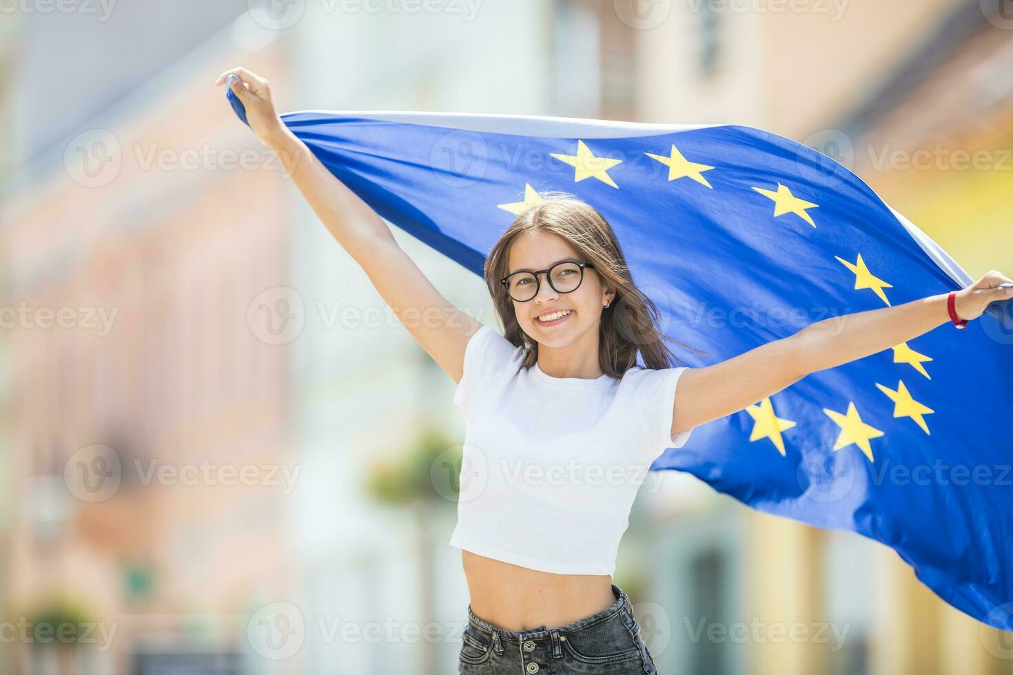 schattig gelukkig jong meisje met de vlag van de Europese unie in de straten ergens in Europa foto