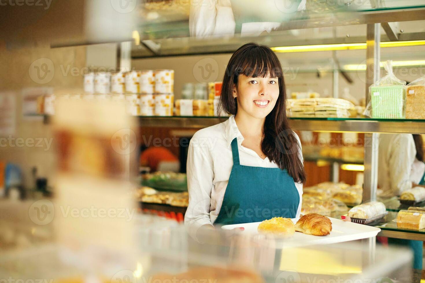 een vrouw in een bakkerij Holding een dienblad van brood foto