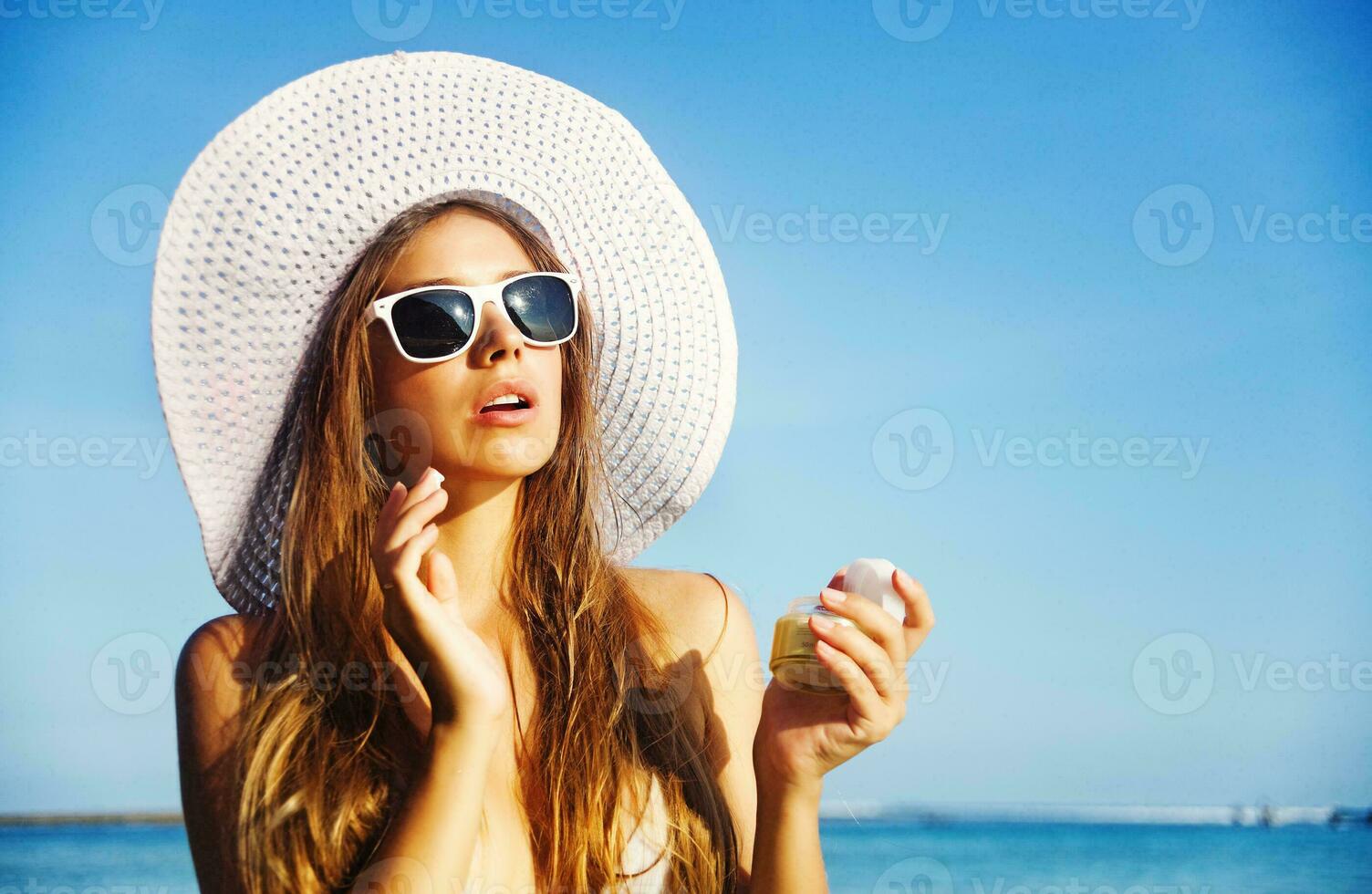 een vrouw in een hoed en zonnebril Aan de strand foto