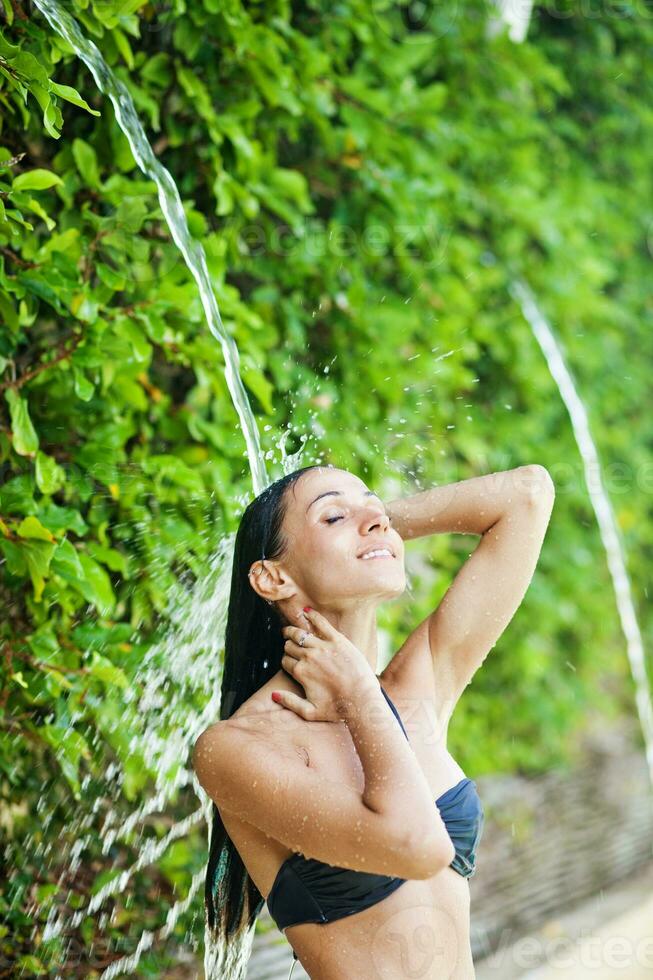 een vrouw in een bikini is spatten water Aan haar hoofd foto