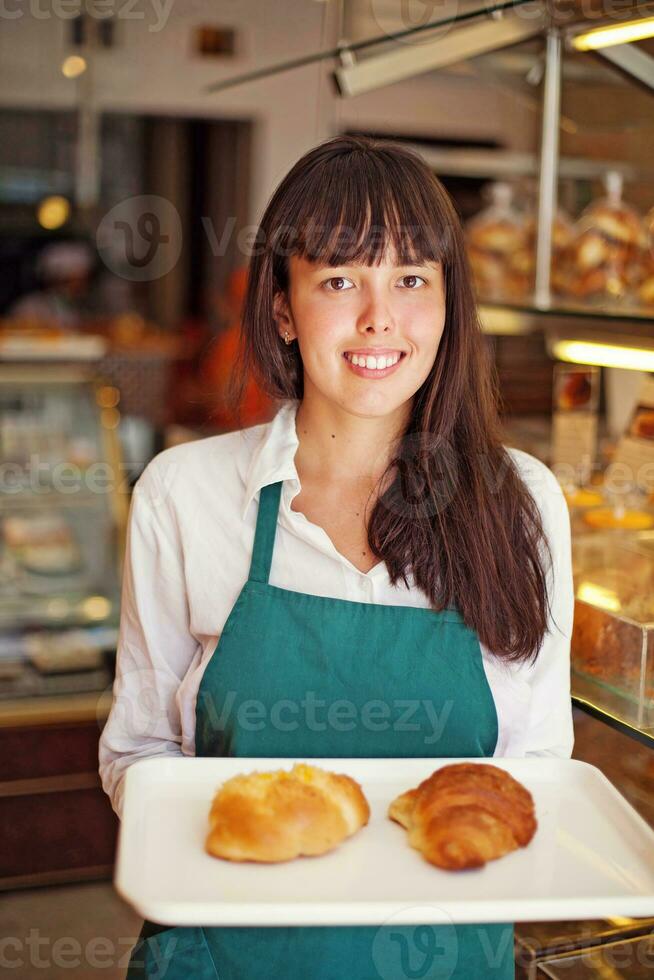 een vrouw Holding een dienblad van gebakken goederen foto