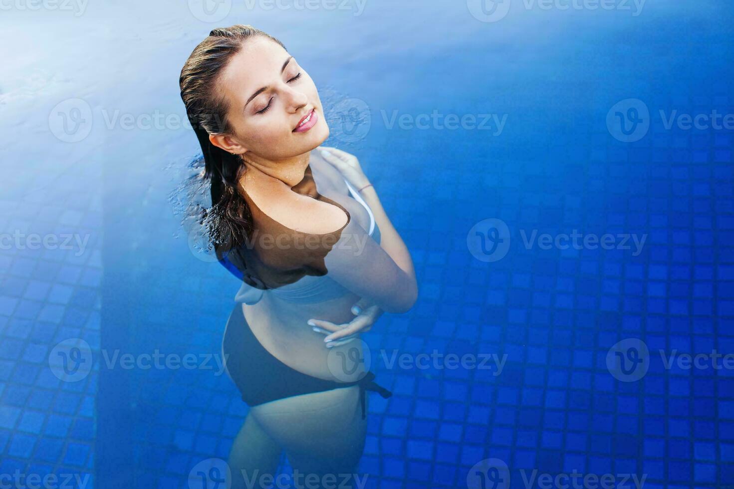 een vrouw in een bikini staand in een zwembad foto