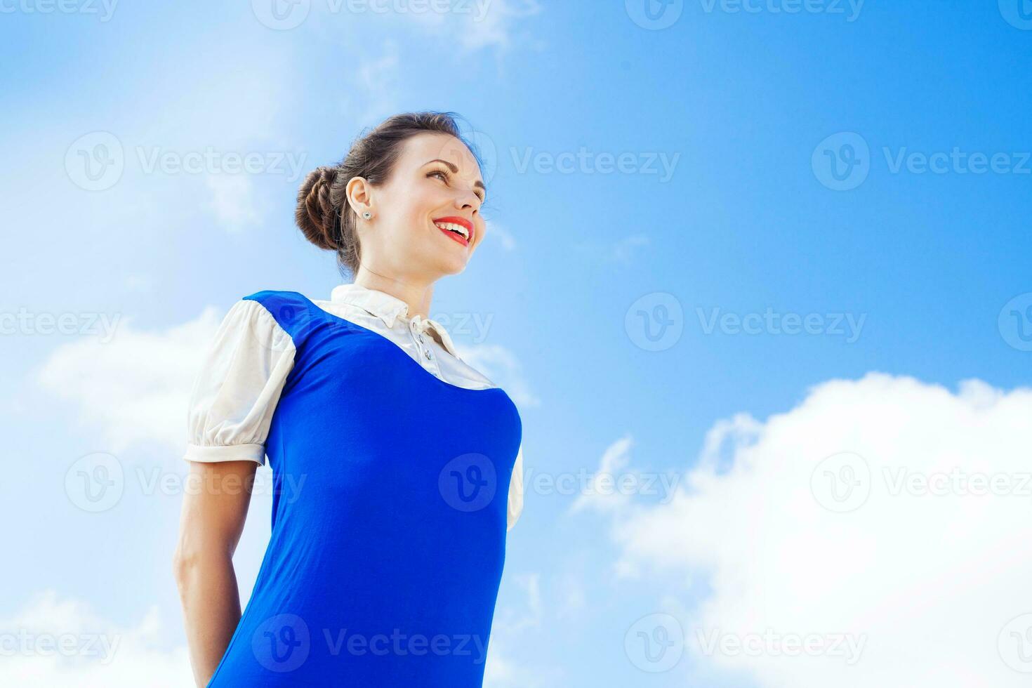 een vrouw in een blauw jurk op zoek omhoog Bij de lucht foto