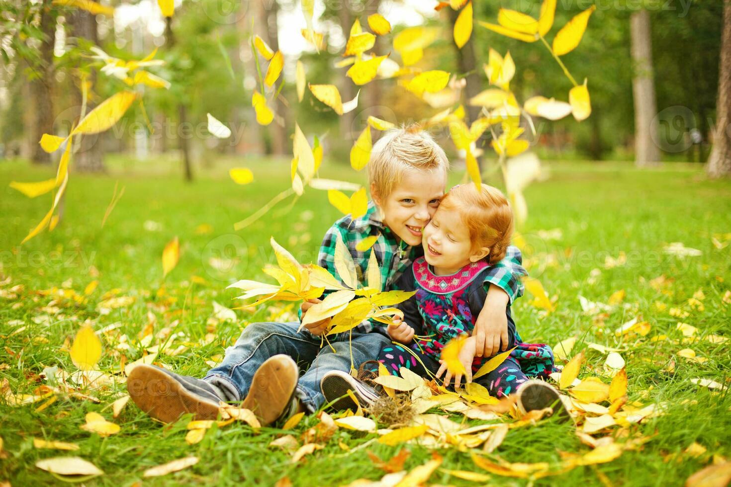 twee kinderen spelen in de gras met bladeren foto