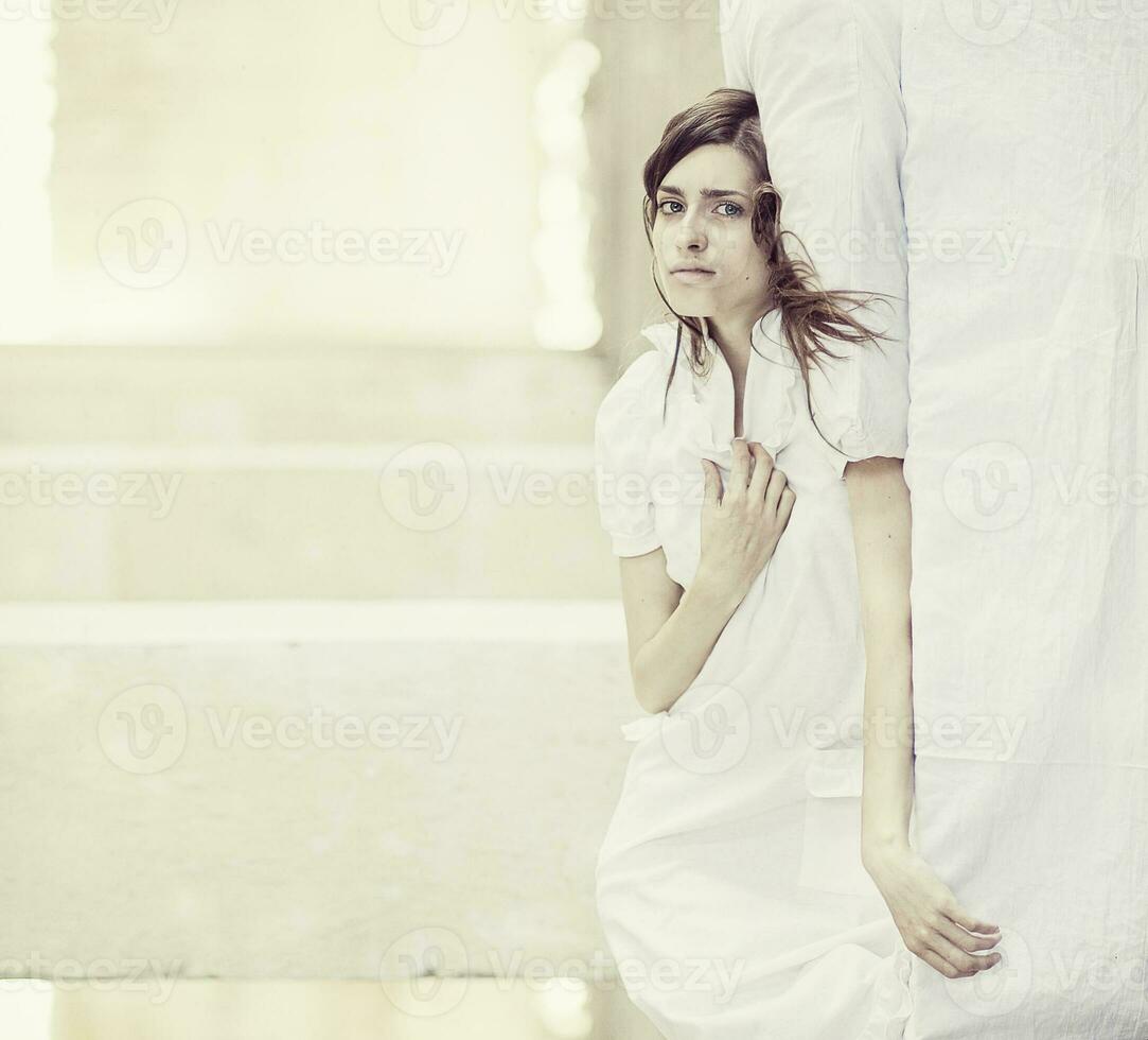 een vrouw in een wit jurk zittend Aan een bed foto