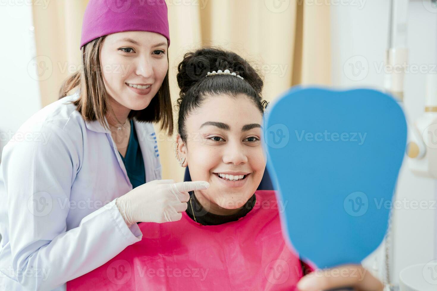 tandarts met tevreden geduldig glimlachen Bij tandheelkundig spiegel, tevreden geduldig in tandheelkundig kliniek op zoek Bij spiegel, vrouw geduldig controle tanden na genezen tanden in tandheelkundig kliniek. foto