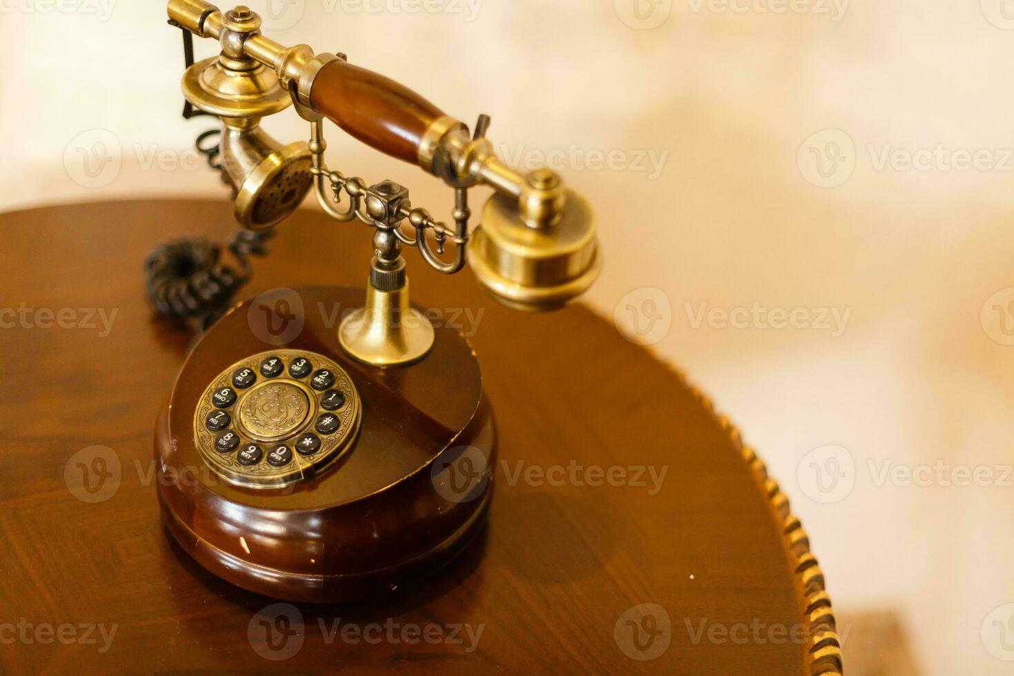 retro telefoon Aan een houten tafel. wijnoogst telefoon van bruin en gouden kleur, wit achtergrond foto