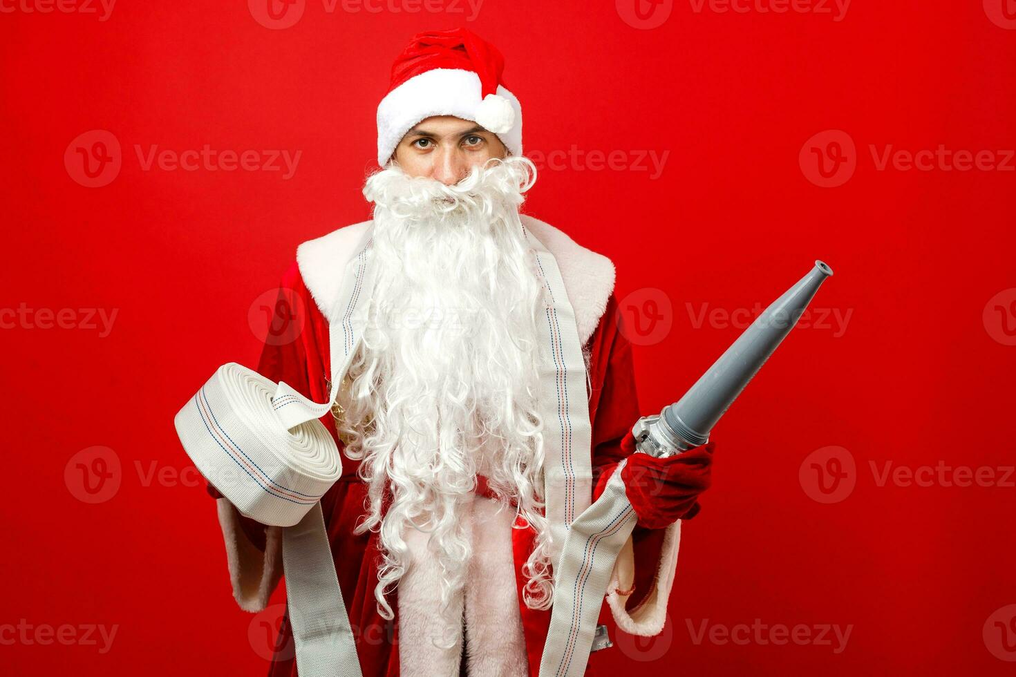 Kerstmis Mens in de kerstman kleren met brand slang staand tegen geïsoleerd wit achtergrond foto