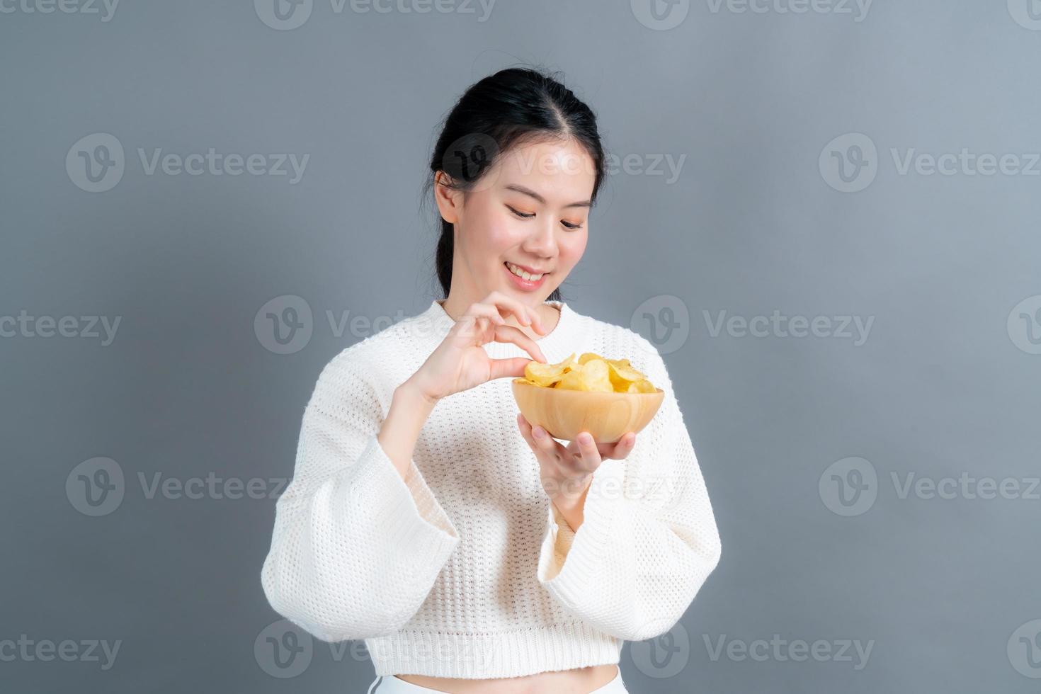 jonge aziatische vrouw eet chips foto