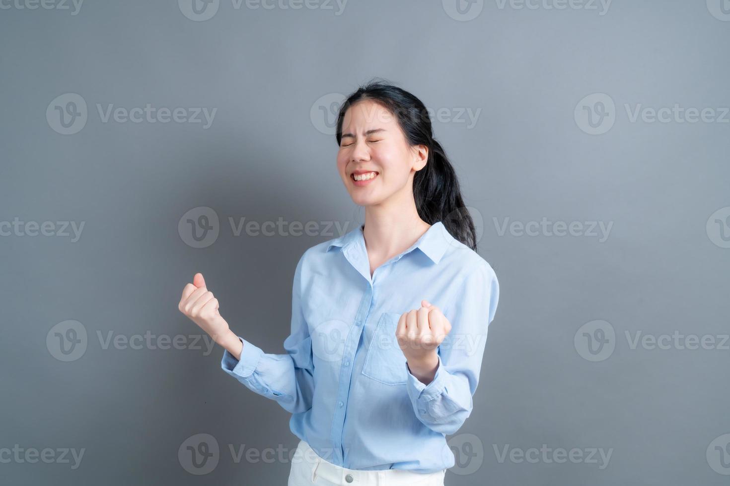 aziatische vrouw die zich verheugt over haar succes en overwinning balde haar vuisten van vreugde. gelukkige vrouw die blij is om haar doel en doelen te bereiken. positieve emoties, gevoelens. foto