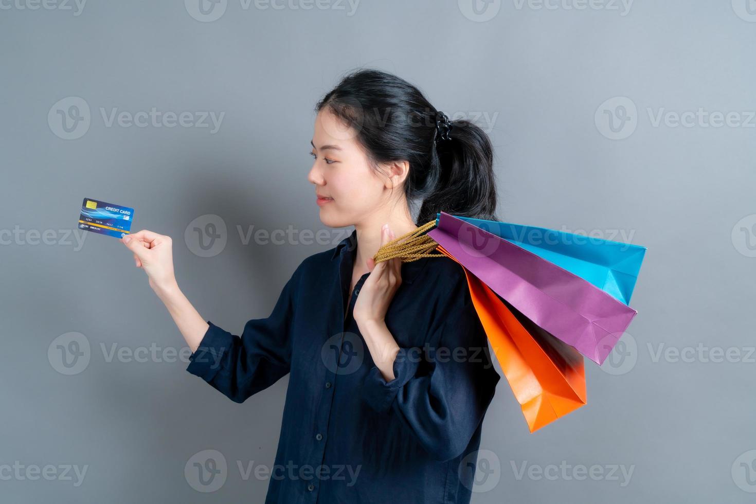 mooie aziatische vrouw met boodschappentassen en creditcard tonen foto