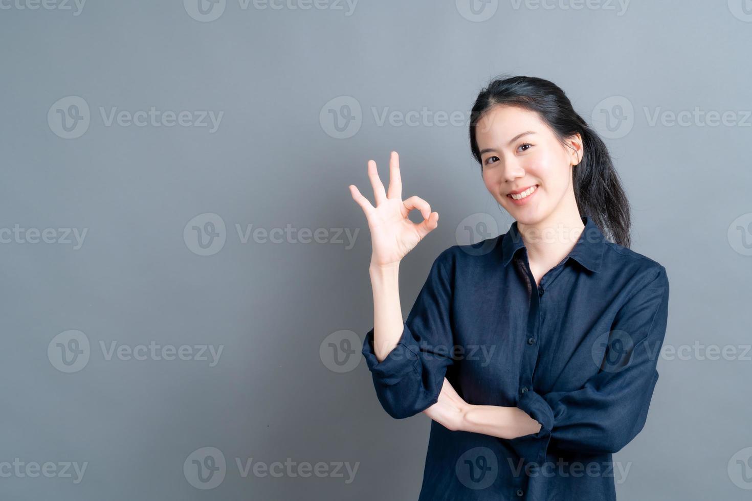 jonge aziatische vrouw die lacht en een goed teken toont foto