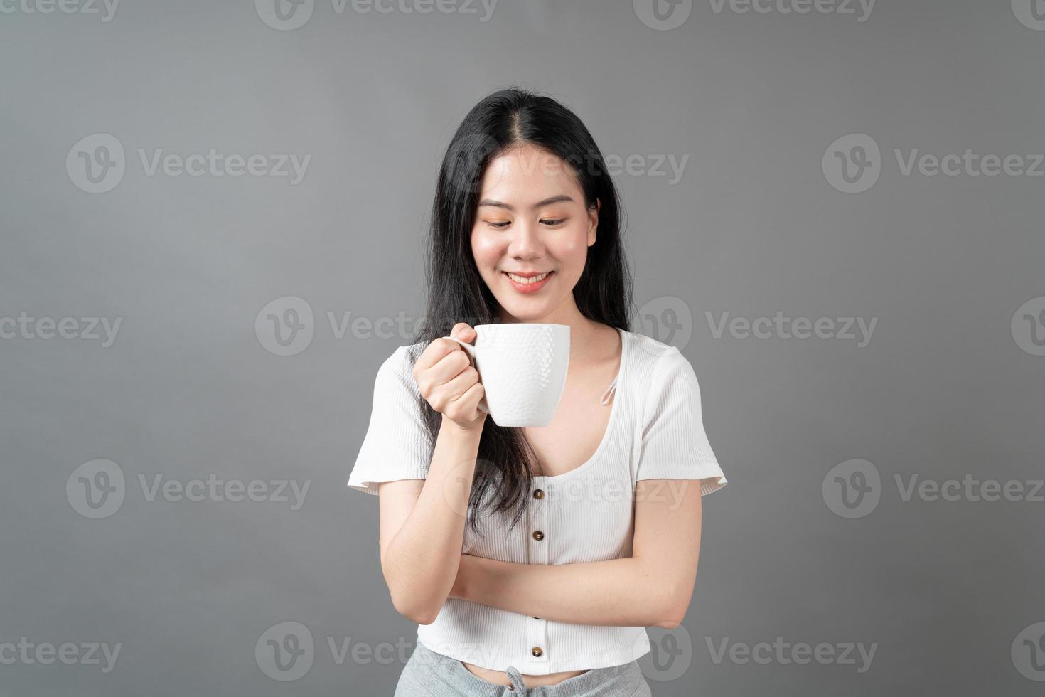 jonge Aziatische vrouw met blij gezicht en hand met koffiekopje foto