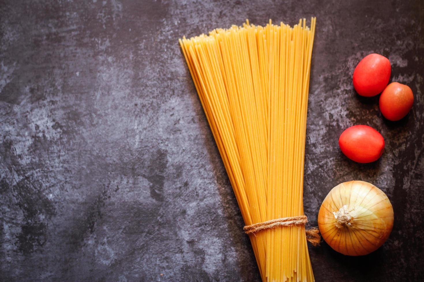 gele lange spaghetti op een rustieke achtergrond. gele Italiaanse pasta. lange spaghetti. rauwe spaghetti bolognese. rauwe spaghetti. voedsel achtergrond concept. Italiaans eten en menuconcept. foto