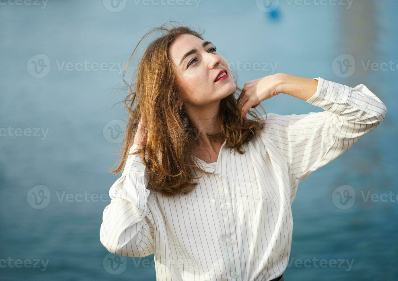 zomer vakantie, vakantie, ontspanning. jong vrouw op zoek Bij blauw lucht. mooi meisje portret. portret van gelukkig glimlachen vrouw wandelen buitenshuis in zee. vrij gelukkig meisje genieten van natuur foto