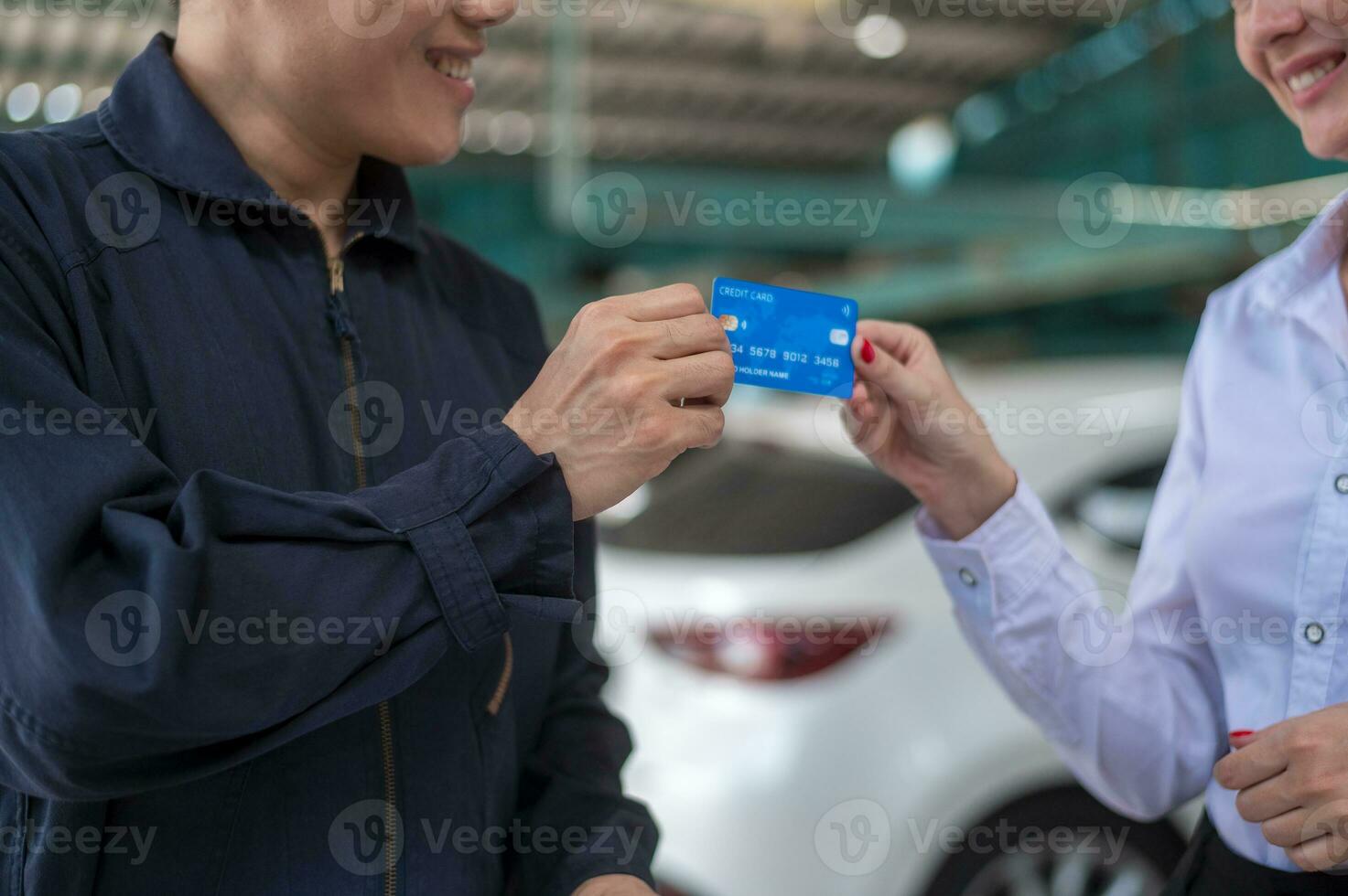 een jong Kaukasisch vrouw betalen via credit kaart naar monteur Mens in reparatie onderhoud winkel foto