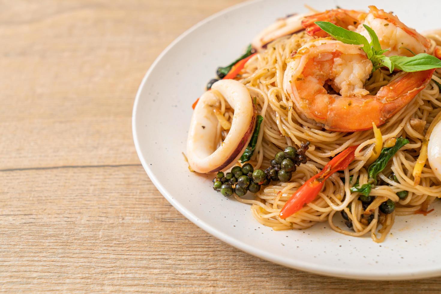 geroerbakte chinese noedels met basilicum, chili, garnalen en inktvis - Aziatisch eten foto