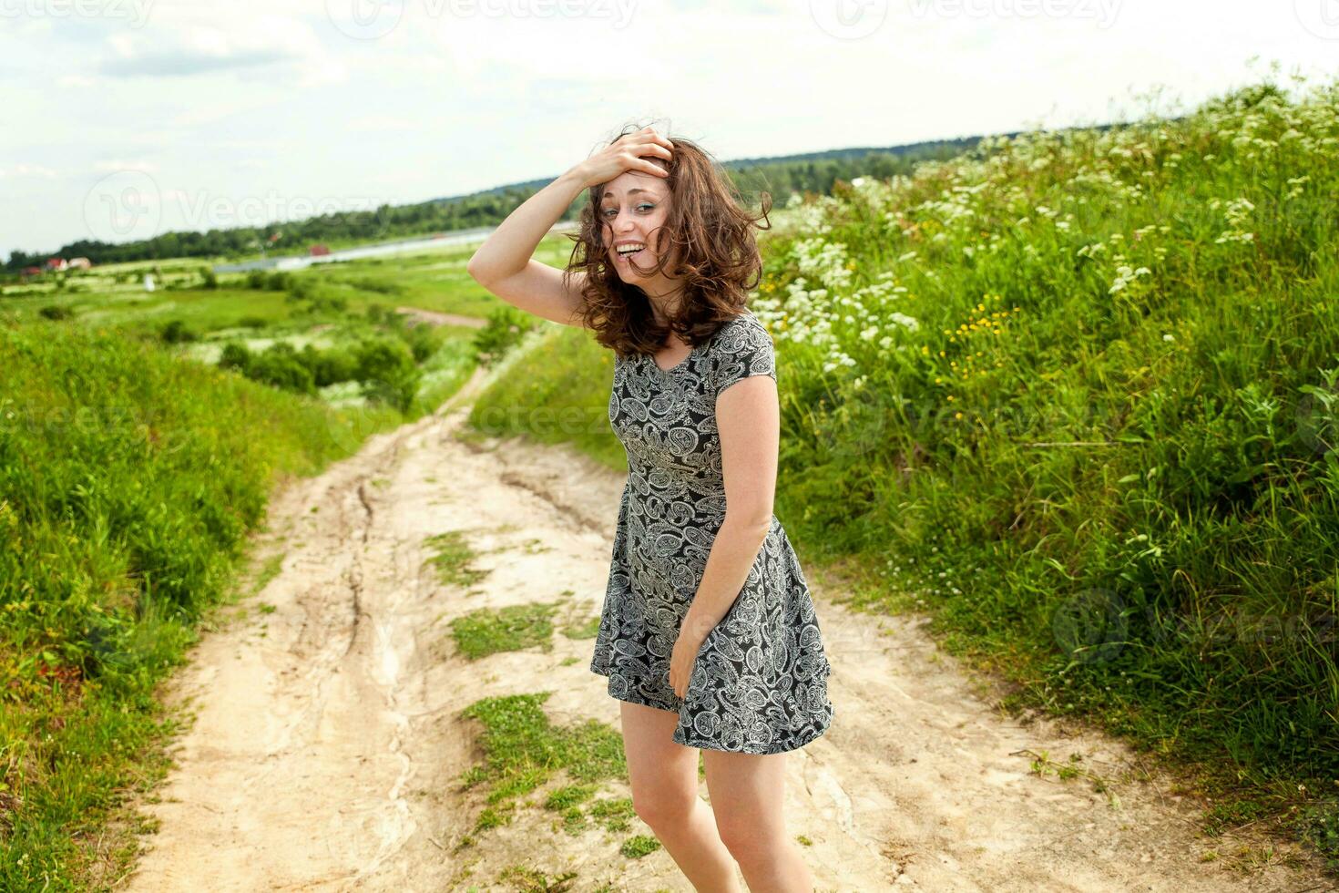 schoonheid meisje buitenshuis genieten van natuur. mooi vrouw jumping Aan zomer veld- met bloeiend wild bloemen, zon licht. vrij gelukkig vrouw. foto