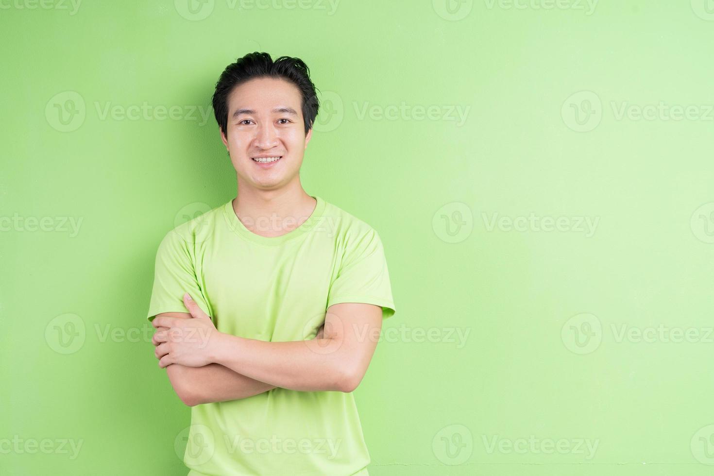 portret van een aziatische man in een groen t-shirt die zich voordeed op een groene achtergrond foto