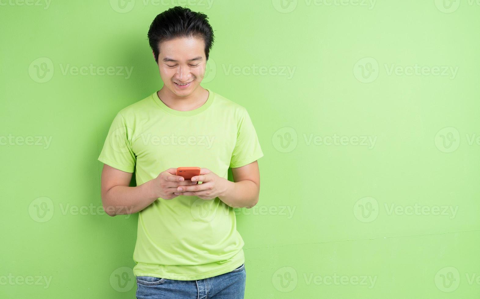 portret van een aziatische man in een groen t-shirt die zich voordeed op een groene achtergrond foto