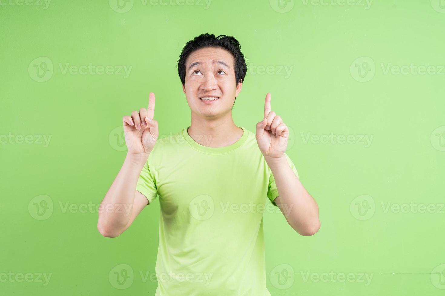 portret van een aziatische man in een groen t-shirt die zich voordeed op een groene achtergrond foto