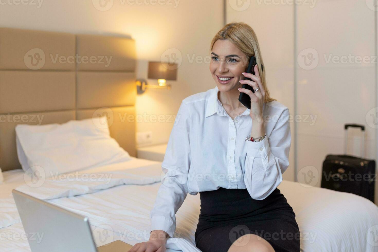 bedrijf, technologie, internet en hotel concept - gelukkig zakenvrouw met laptop computer zittend in hotel Aan bed en werken laat in hotel kamer, met haar laptop computer, document en papierwerk foto