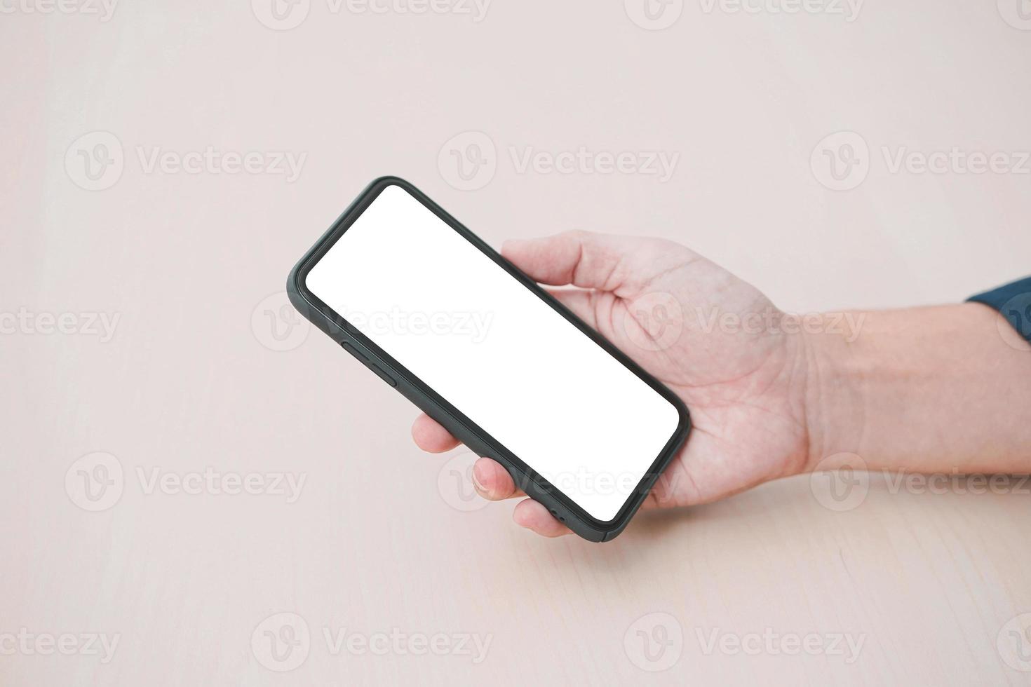 mockup afbeelding leeg scherm smartphone. lege witte smartphone gehouden door mannenhand op houten achtergrond. foto
