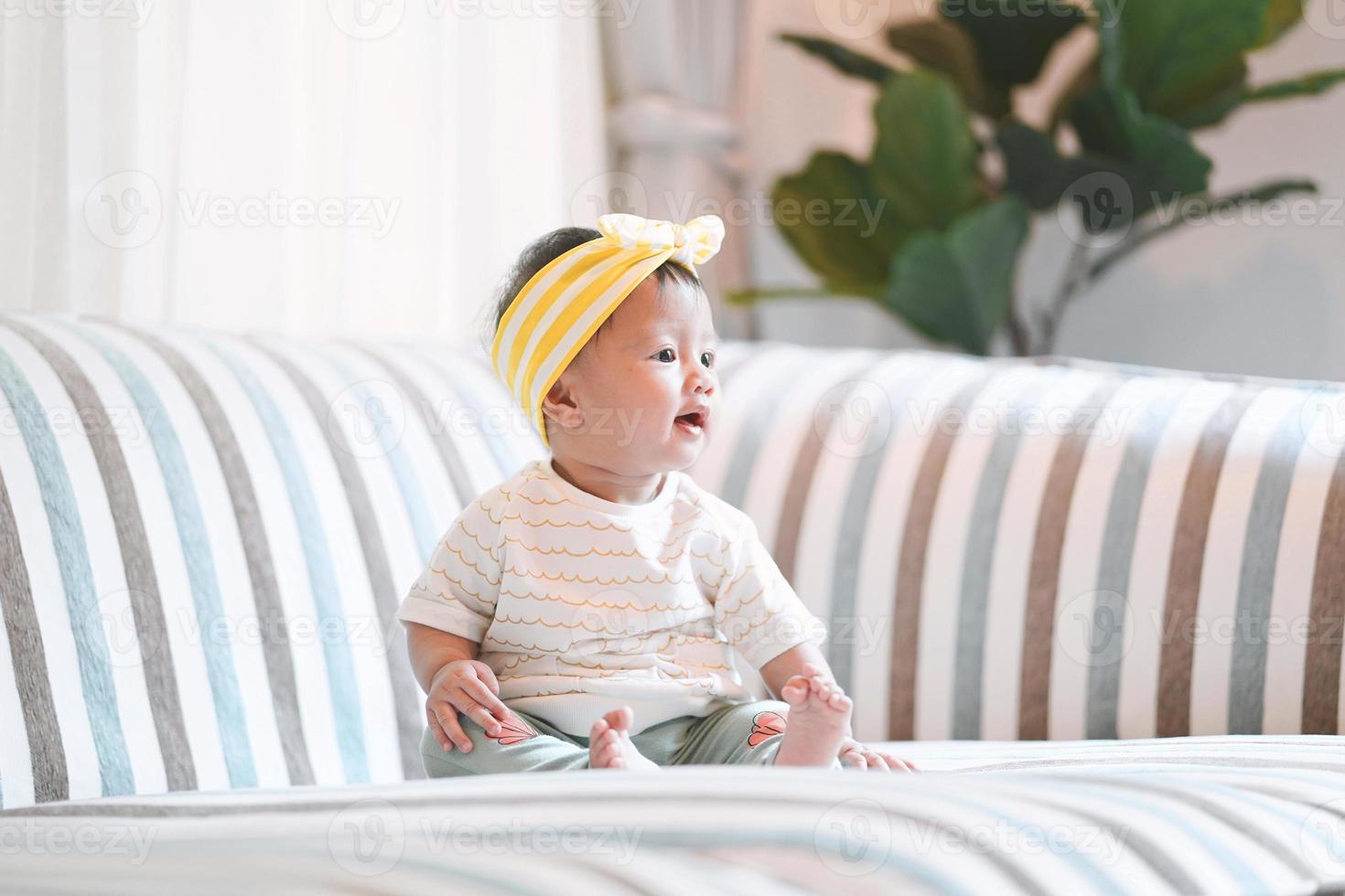 Aziatische babymeisje aanbrengen op een bank thuis. foto