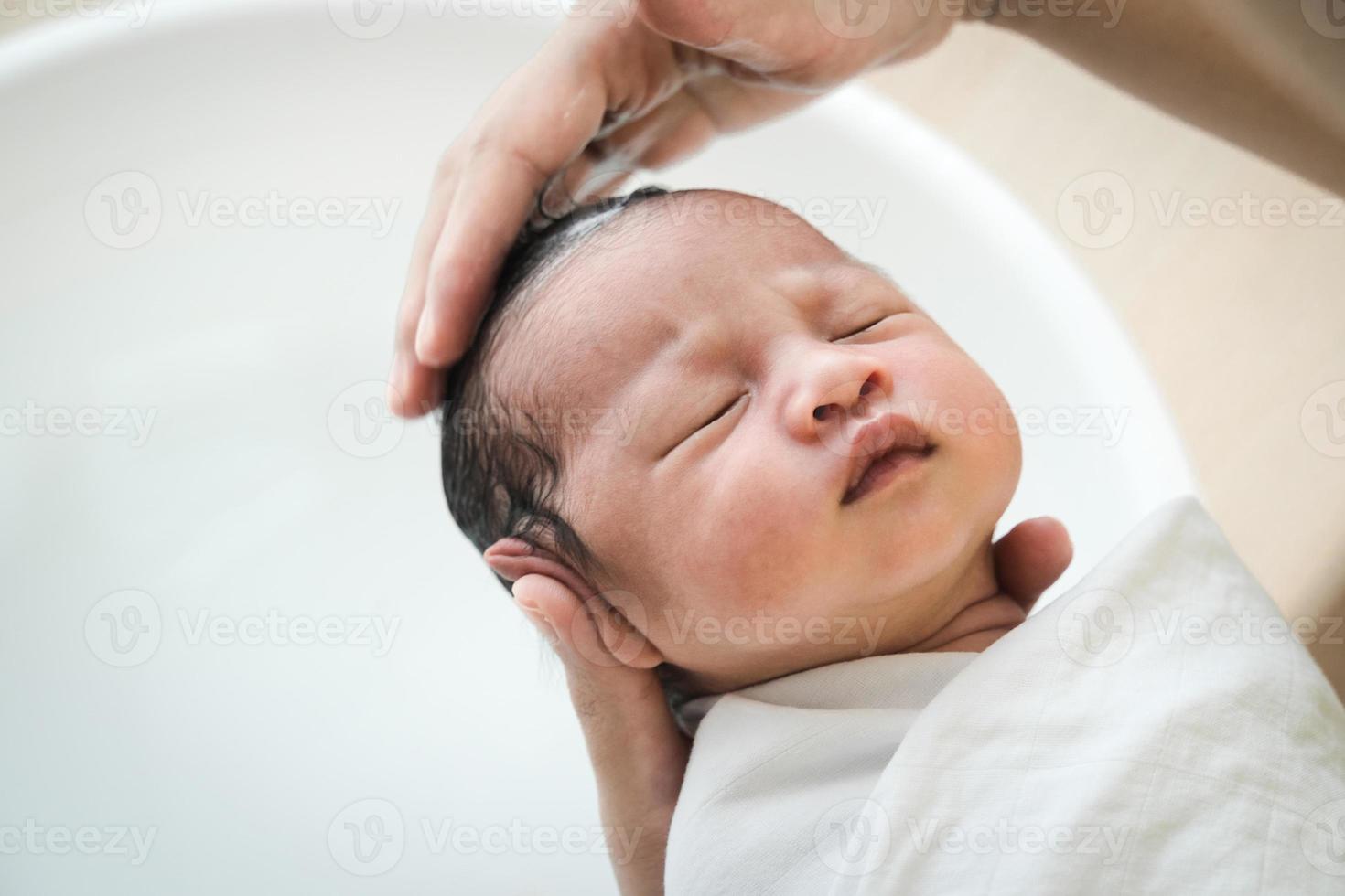 moeder wast babyhaar. moeder die haar babyhaar schoonmaakt. foto