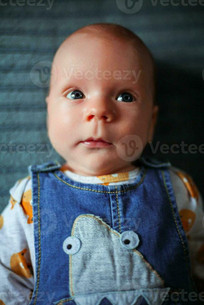 een weinig jongen, pasgeboren, met mooi blauw ogen looks in de afstand foto