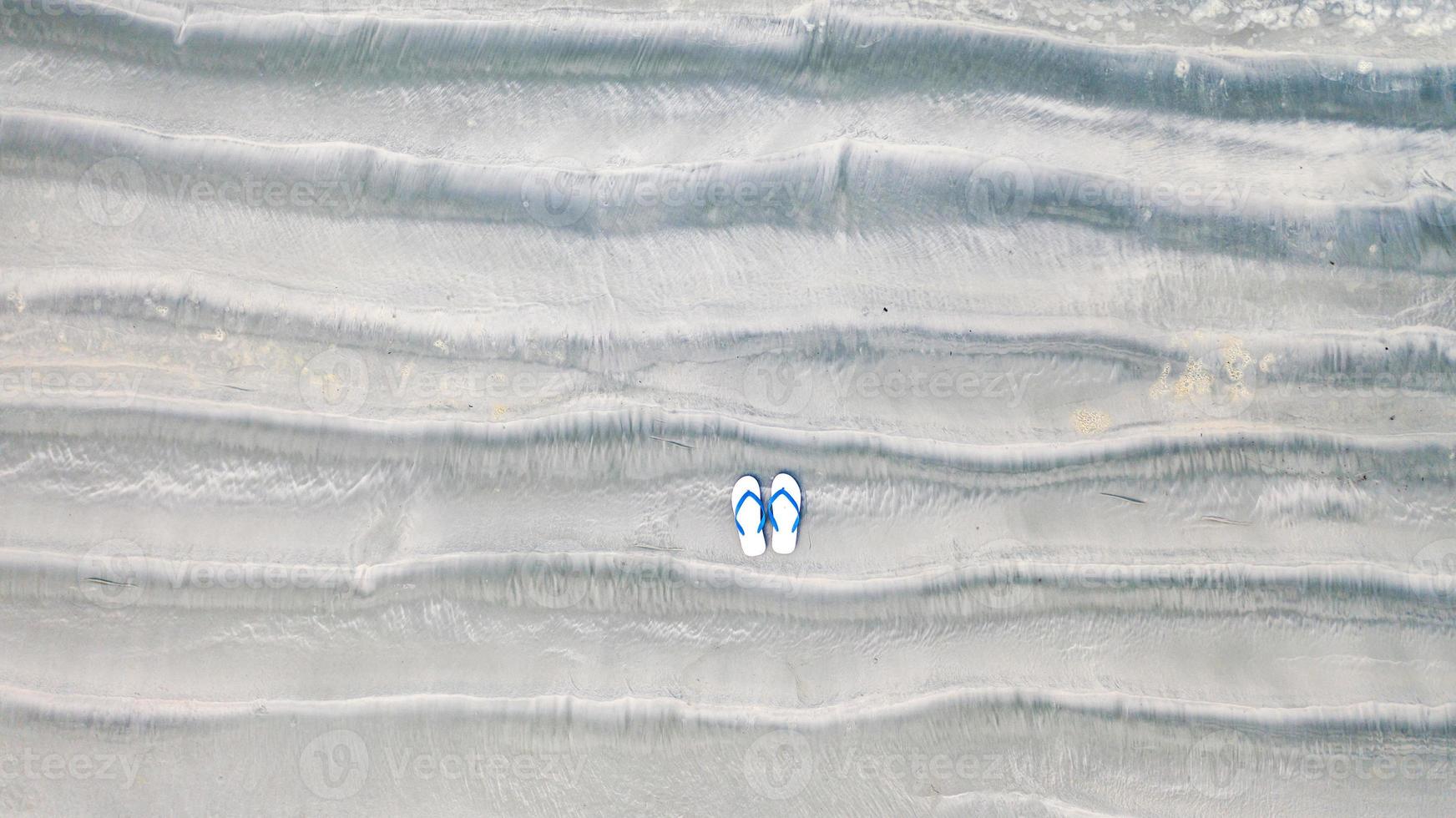 flip-flops op zandstrand, zomervakantie achtergrond, bovenaanzicht vanuit de lucht foto