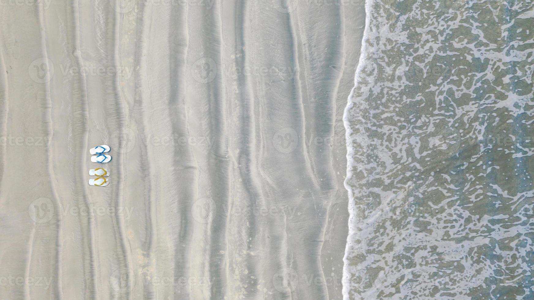 flip-flops op zandstrand, zomervakantie achtergrond, bovenaanzicht vanuit de lucht foto