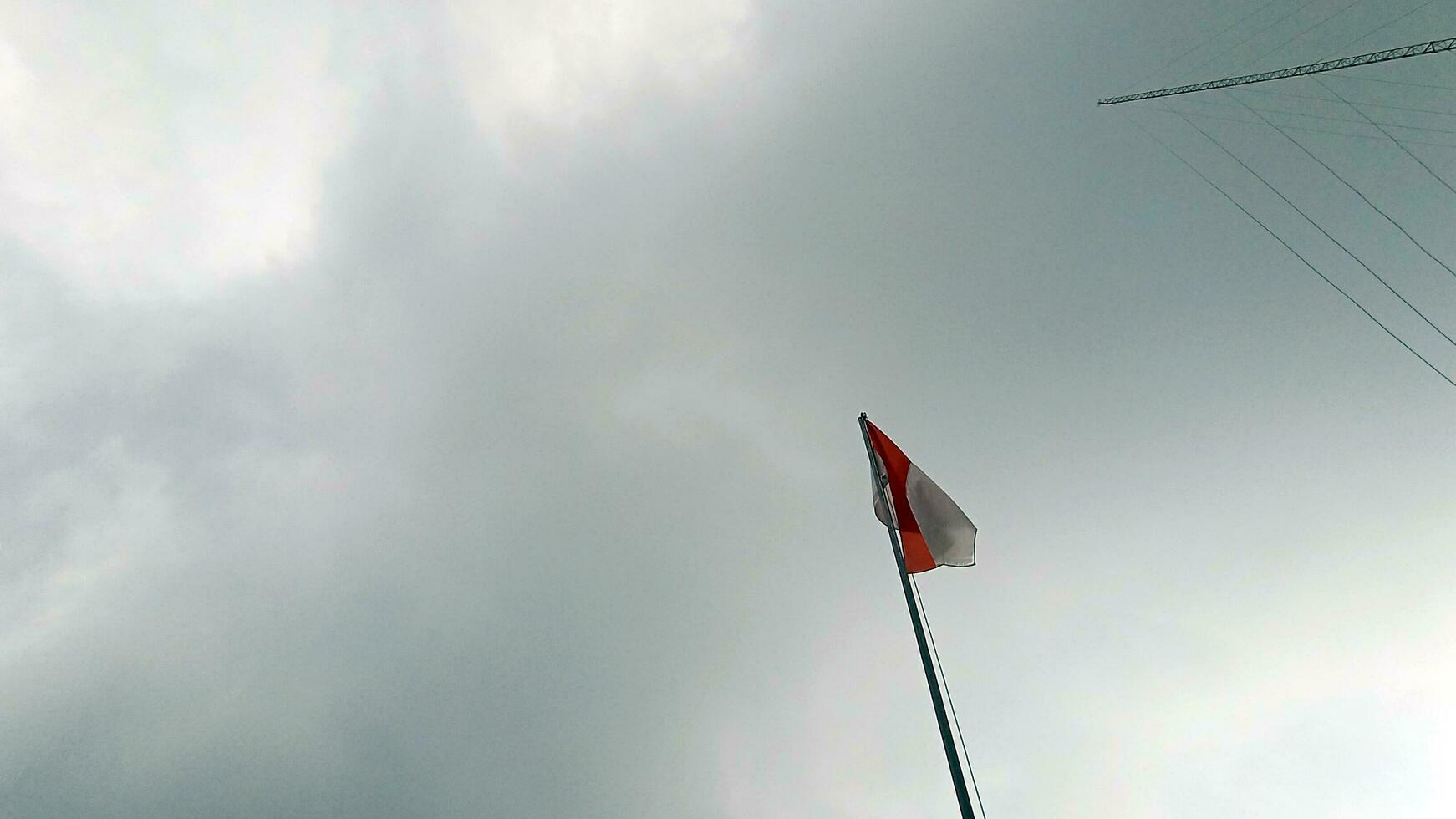 Indonesisch vlag Aan een bewolkt lucht foto