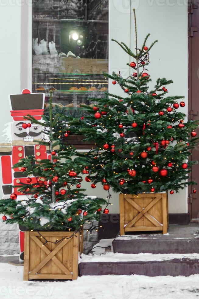 Kerstmis bomen versierd met rood ballonnen in voorkant van de Ingang naar de cafe. straat Kerstmis decoraties. Kerstmis bomen en een houten notenkraker foto