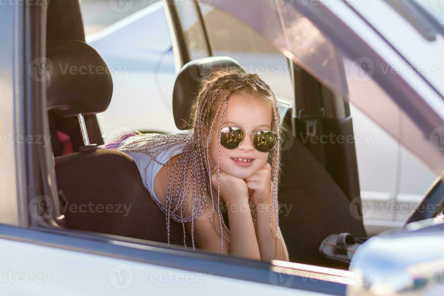 glimlachen tiener- meisje met afro-vlechten zit in de passagier gedeelte van een auto Aan een heet zomer dag. weg reis foto