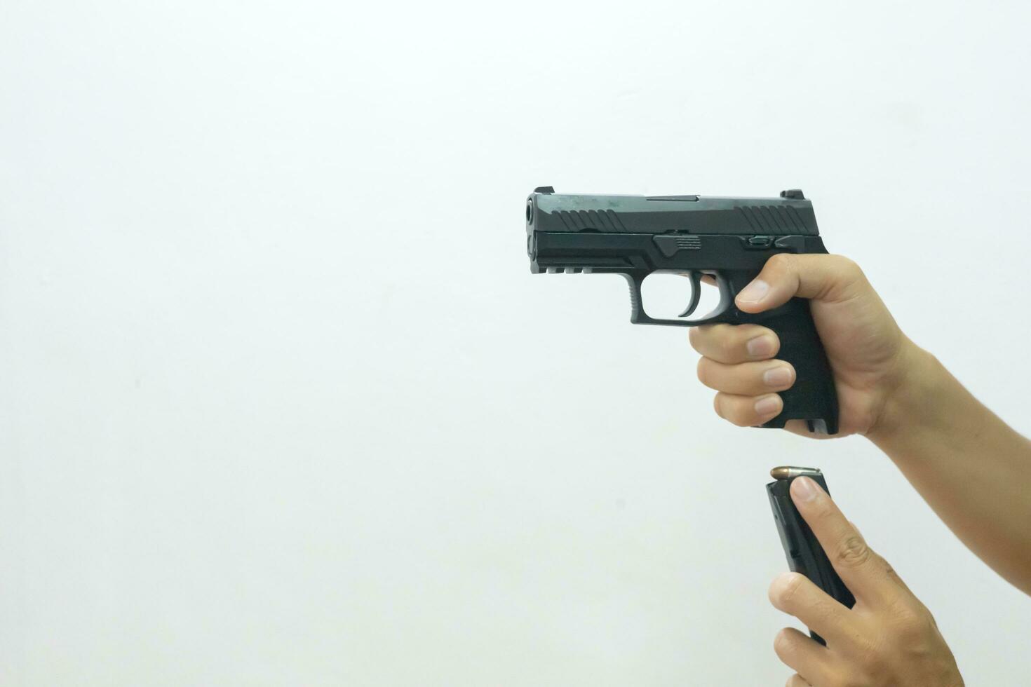 een hand- Holding de geweer richten vooruit en de andere invoegen de mag in de geweer Aan een wit achtergrond. foto
