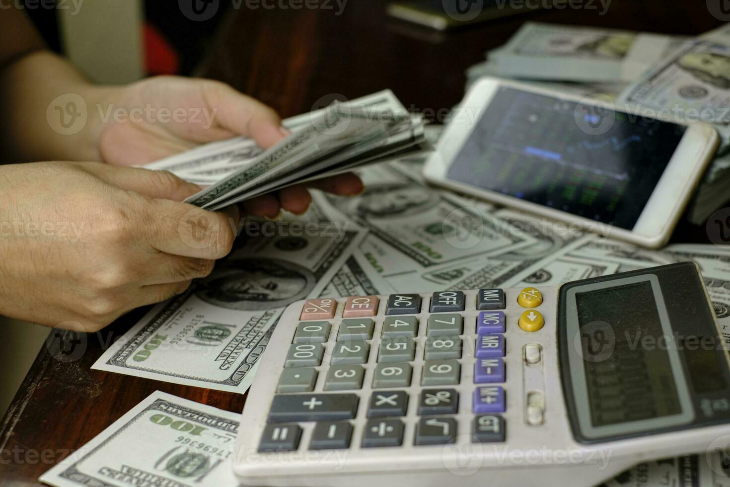 zakenlieden vrouwen tellen geld op een stapel van 100 Amerikaanse dollars bankbiljettennote foto