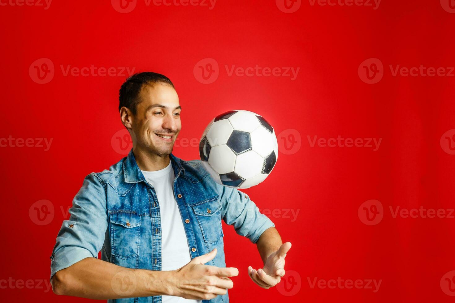 knap Mens Holding een voetbal bal over- rood achtergrondkleur foto