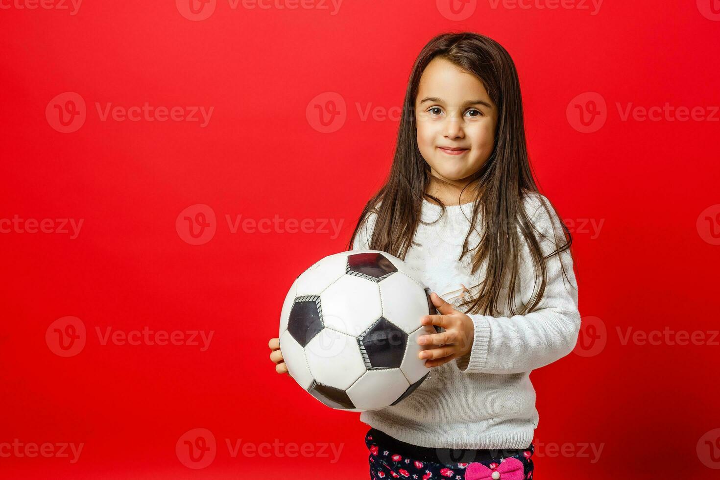 weinig meisje met de bal over- rood backgrounf foto