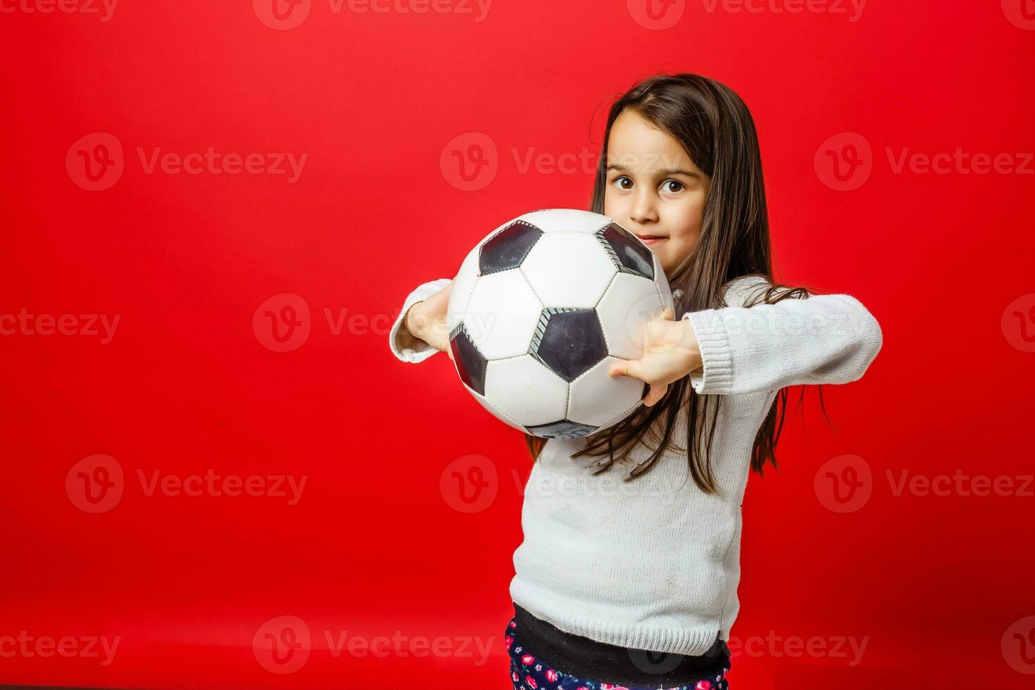 weinig meisje met de bal over- rood backgrounf foto