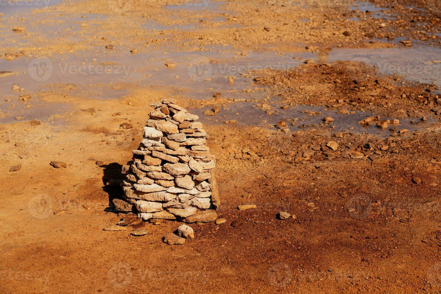 modderig grond met voorjaar water, met stapels van stenen Aan een kant. foto