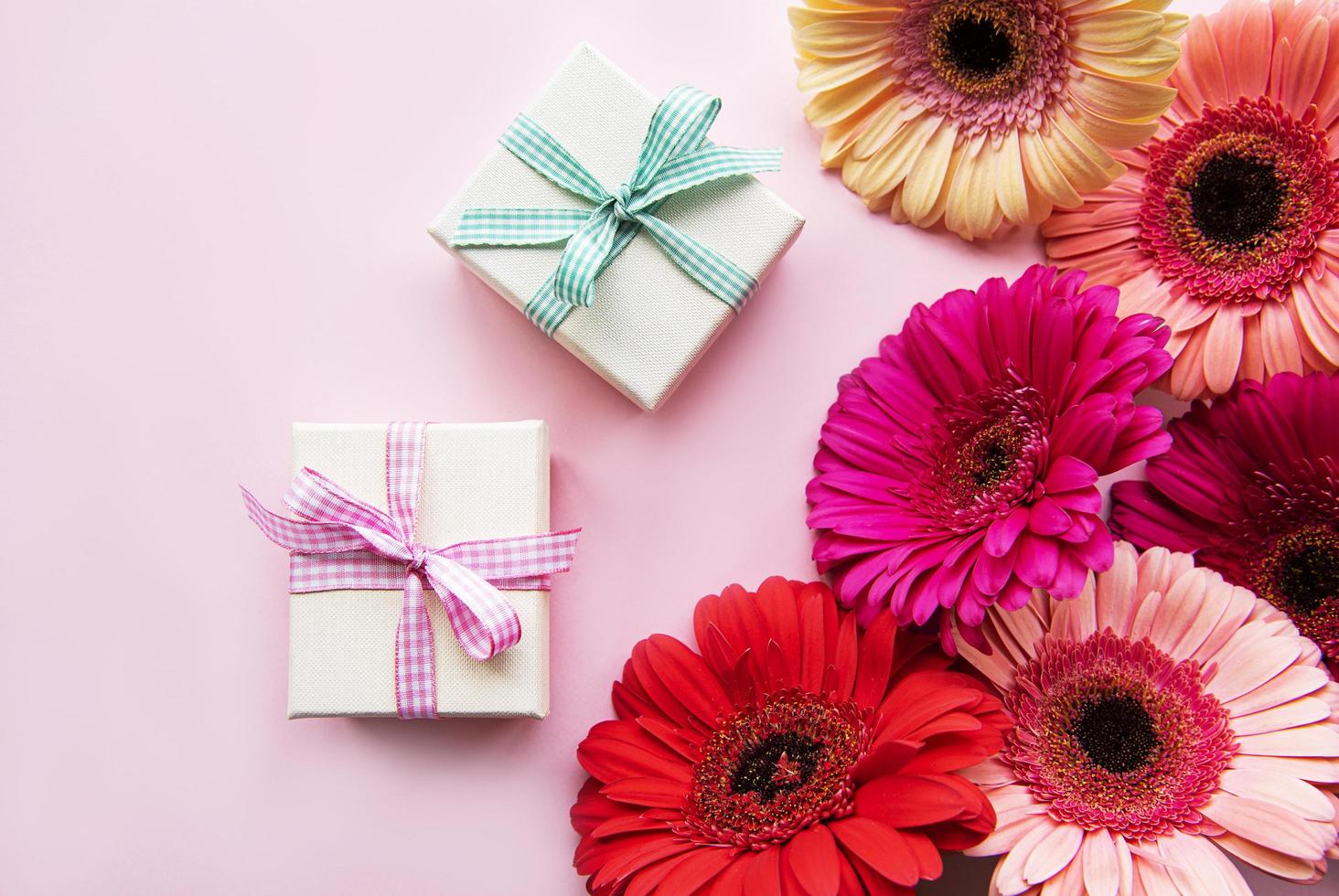 gerbera bloemen en geschenkdozen op een roze foto