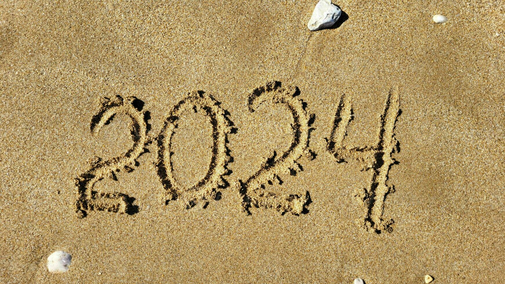 de getallen 2024 zijn geschreven Aan de zanderig strand. de concept van de nieuw jaar foto