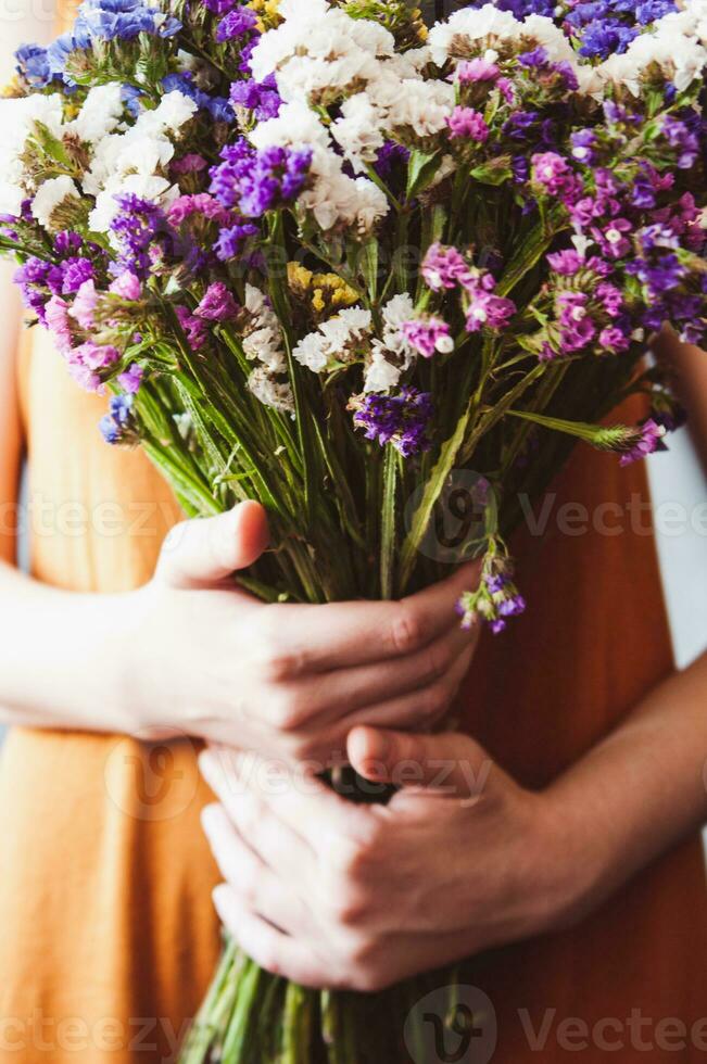 meisje Holding een boeket van limonium bloemen in haar handen. verscheidenheid van limonium sinuatum, statice Salem bloemen of zee lavendel foto