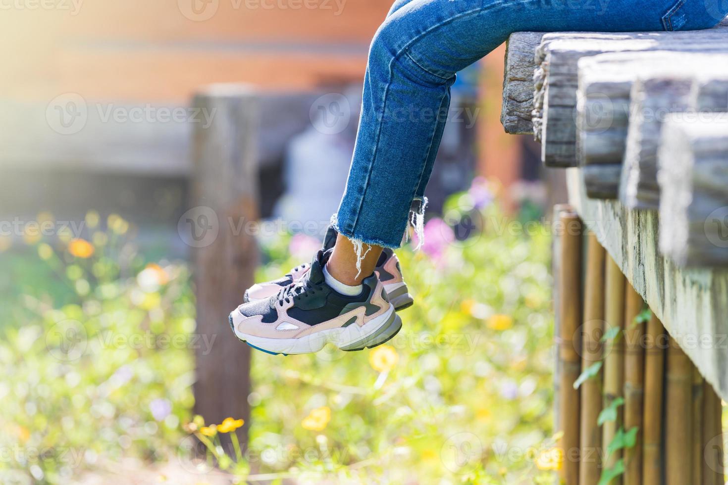 vrouw zit op de houten brug en hangt benen in bloementuin foto