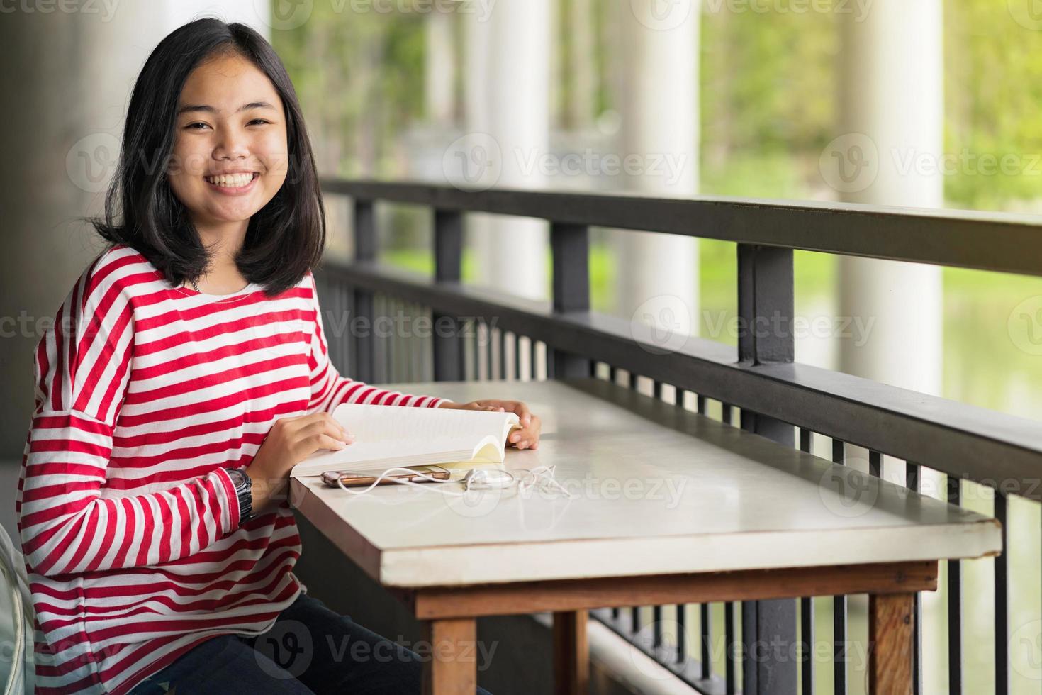 Aziatische student meisje zit en lacht lezen van een boek in de school foto