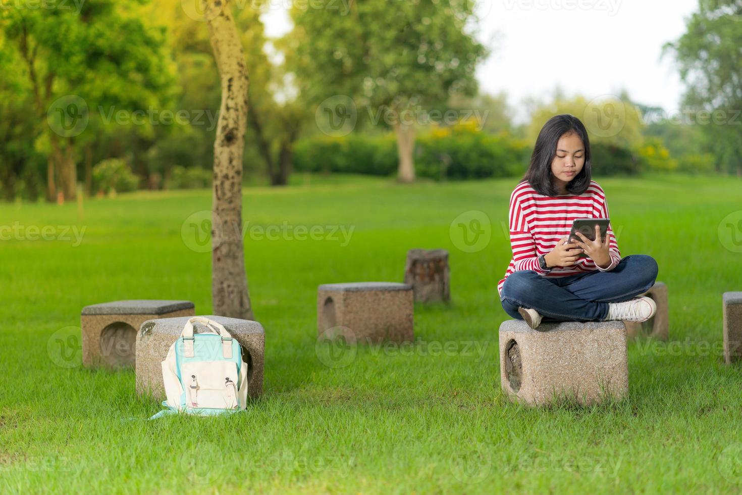 Aziatisch studentenmeisje dat een digitale tablet in het schoolpark gebruikt op een zonnige zomerdag foto