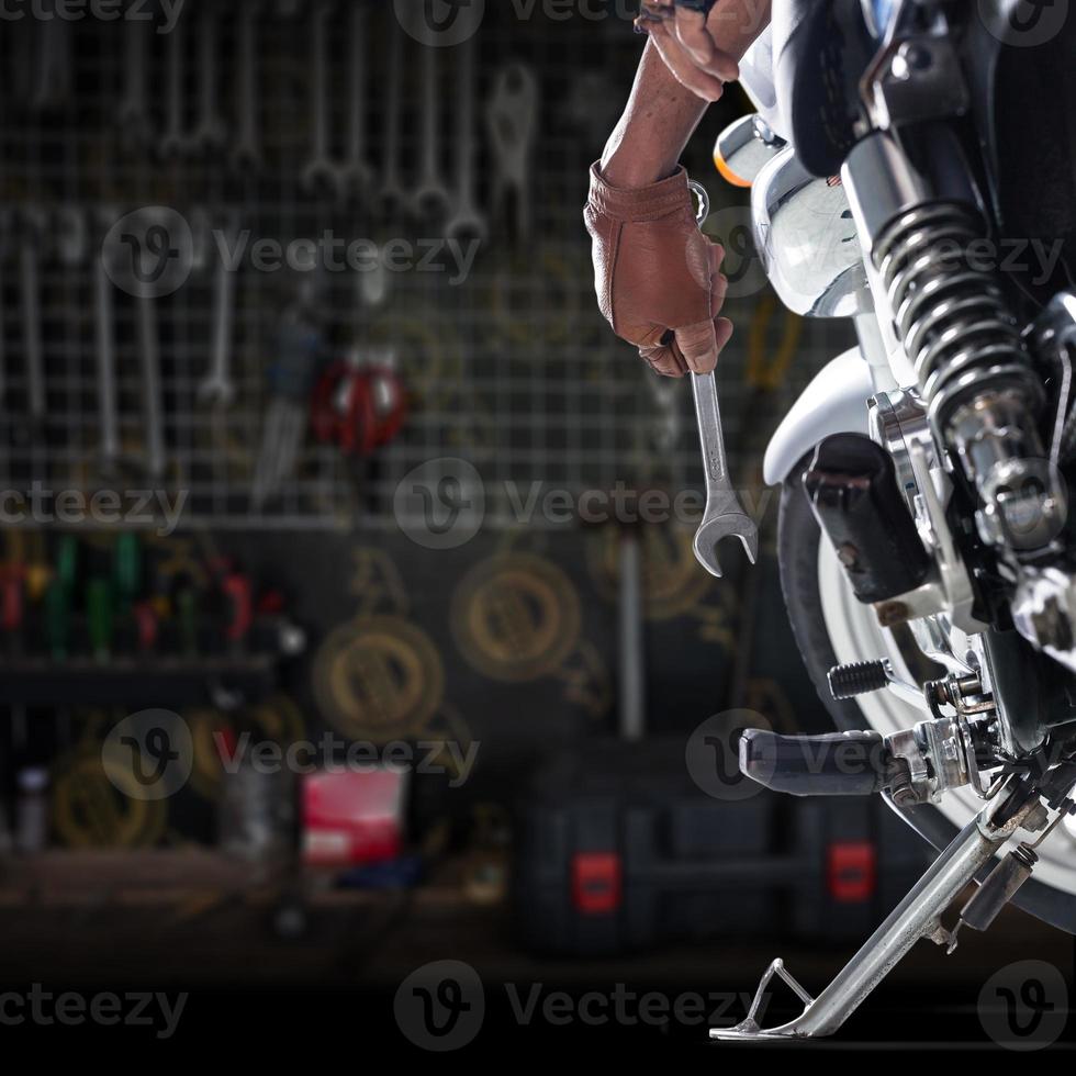 bijgesneden weergave van monteur met een moersleutel op een motorfiets foto